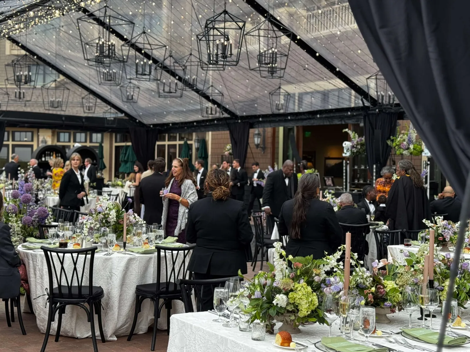 Elegant corporate dinner beneath glass ceilings and chandeliers with floral centerpieces