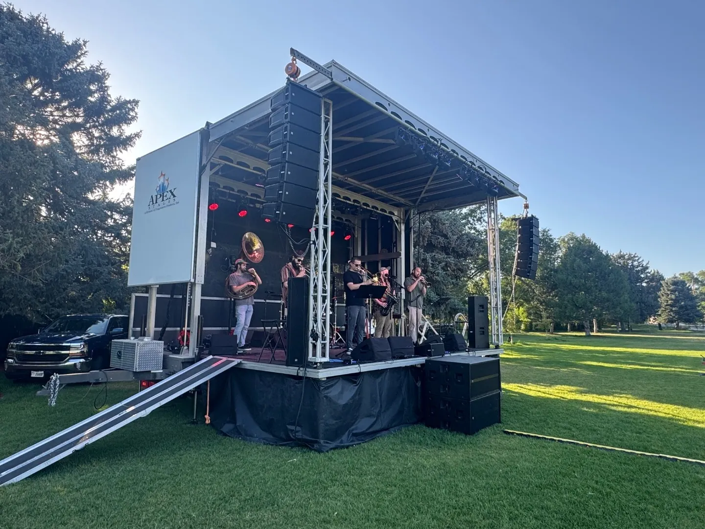 Live band performing on an outdoor mobile stage with RCF line arrays