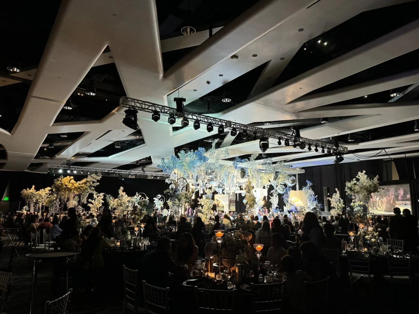 Black-tie gala in a hotel ballroom with floral centrepieces and full stage lighting