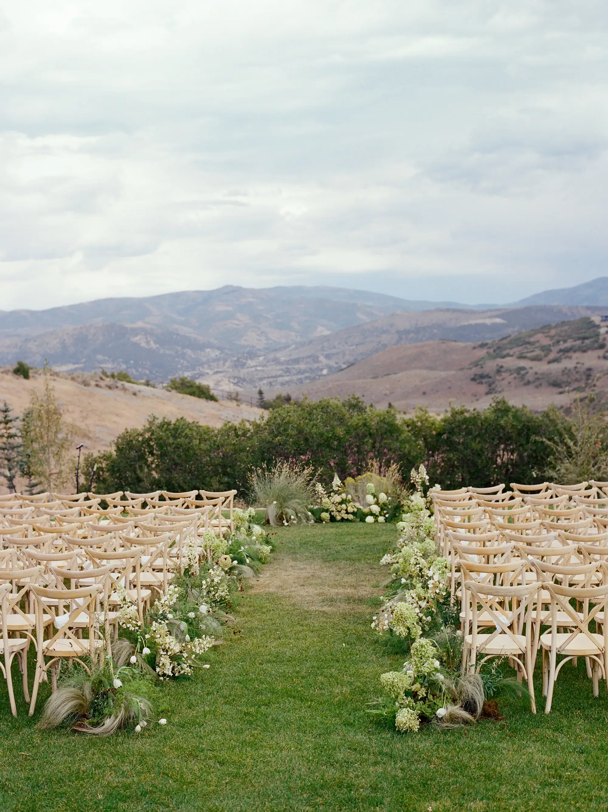 Outdoor wedding ceremony aisle lined with white florals overlooking Idaho mountain foothills