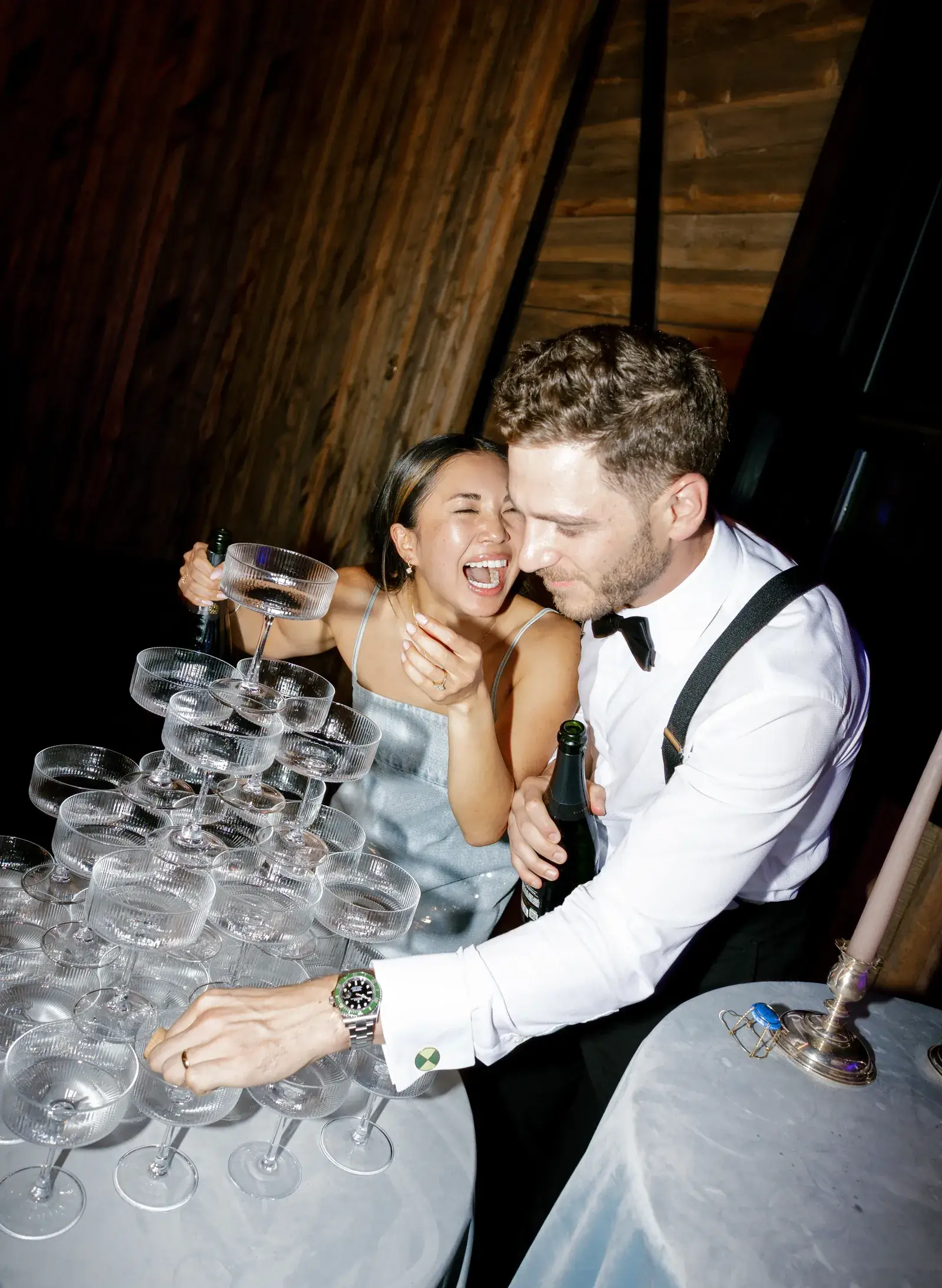 Bride and groom pouring a champagne coupe tower at an elegant wedding reception