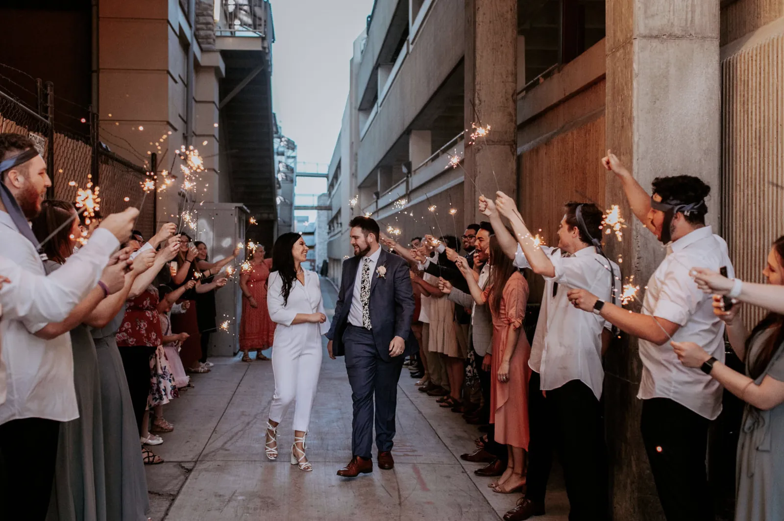 Newlyweds kissing during a sparkler exit surrounded by cheering guests